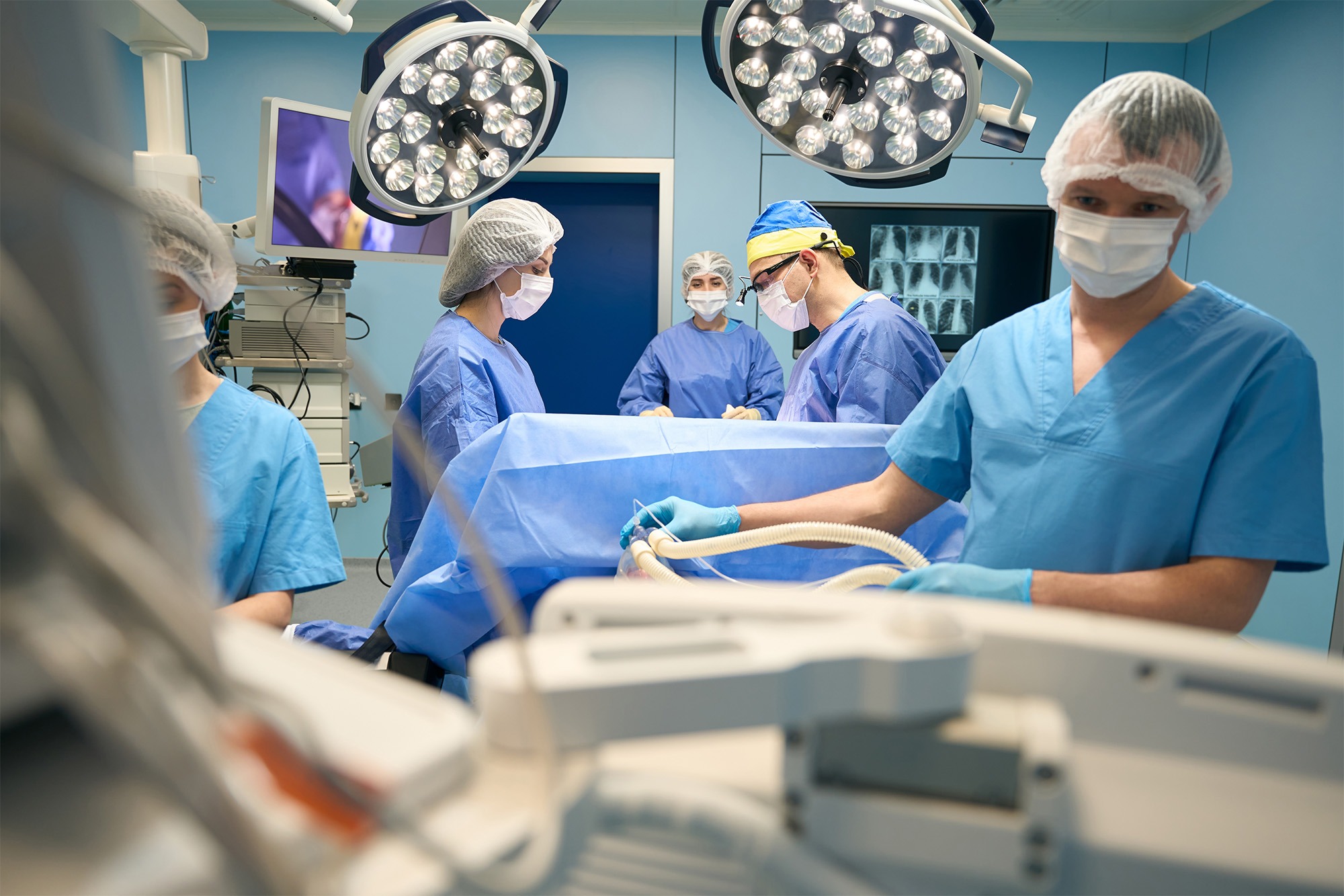 A team of medical professionals in scrubs and masks preparing for surgery and providing anesthesia care in an operating room, representing Poliran Health, a trusted Anesthesia Staffing Company.