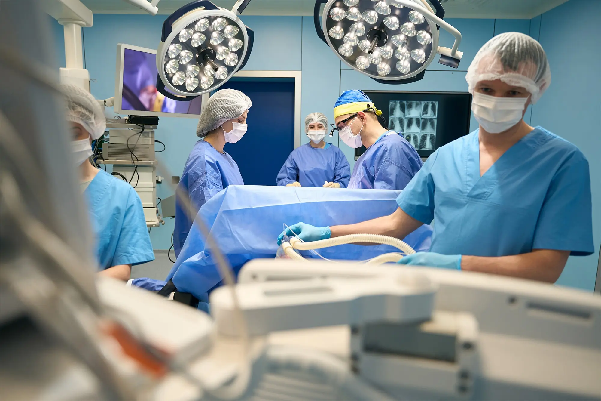 A team of medical professionals in scrubs and masks preparing for surgery and providing anesthesia care in an operating room, representing Poliran Health, a trusted Anesthesia Staffing Company.