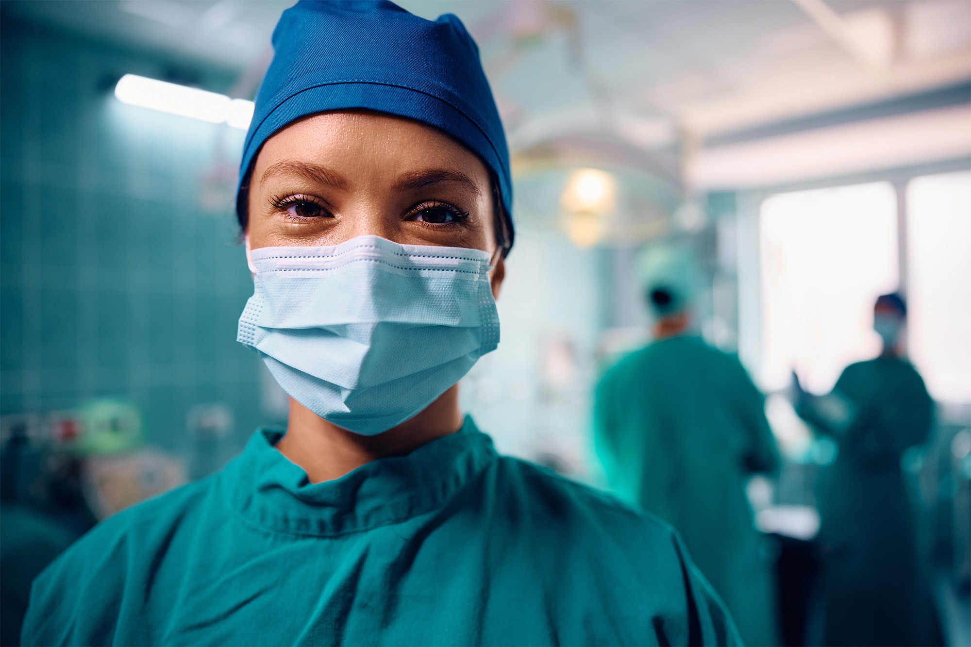 Smiling healthcare professionals in surgical scrubs and mask in an operating room, representing Poliran Health, an Anesthesia Staffing Company focused on teamwork and care.