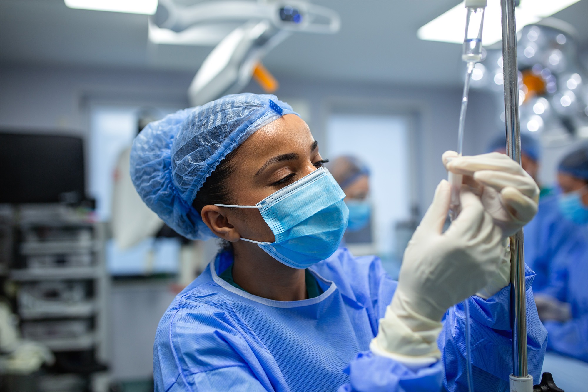 A Locum Tenens CRNA in scrubs and a blue mask prepares an IV drip in a sterile environment, ensuring patient safety and quality care.